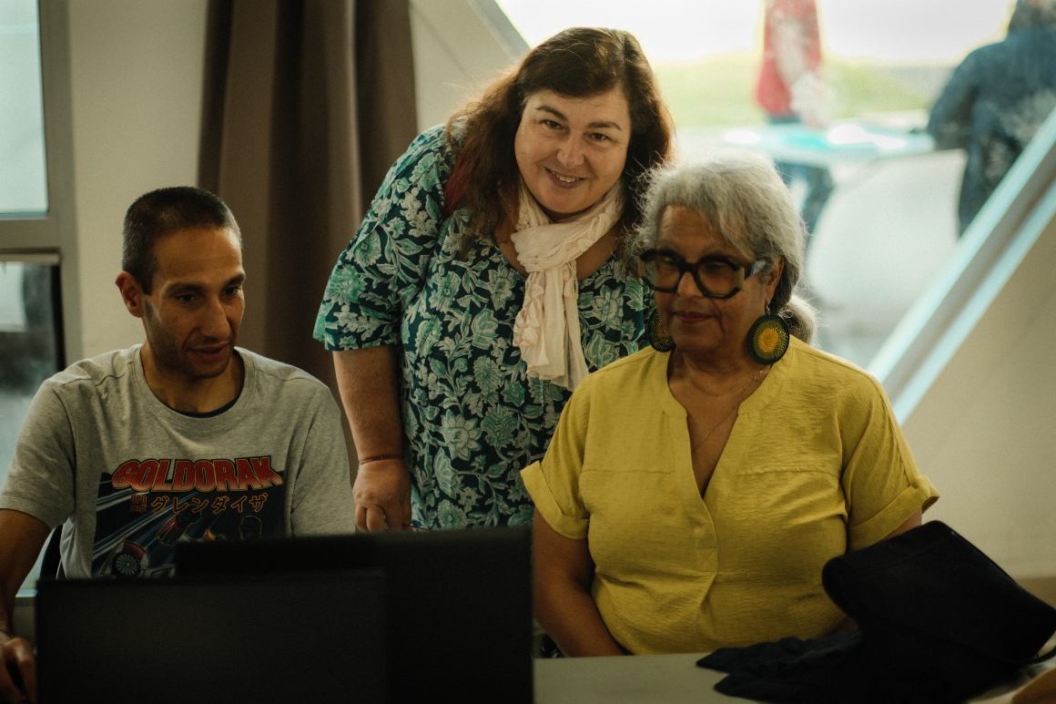 Three people working together around a computer